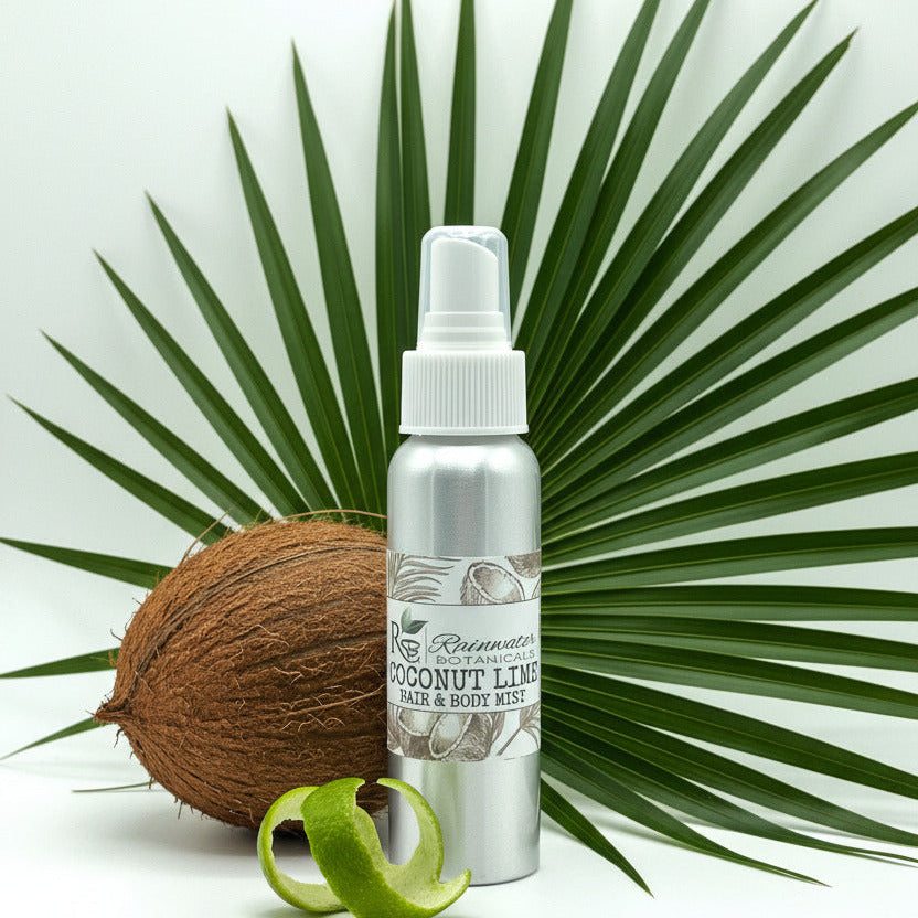 A silver aluminum spray bottle of Rainwater Botanicals Coconut Lime Hair & Body Mist with a white plastic pump dispenser and a decorative label featuring coconut illustrations.